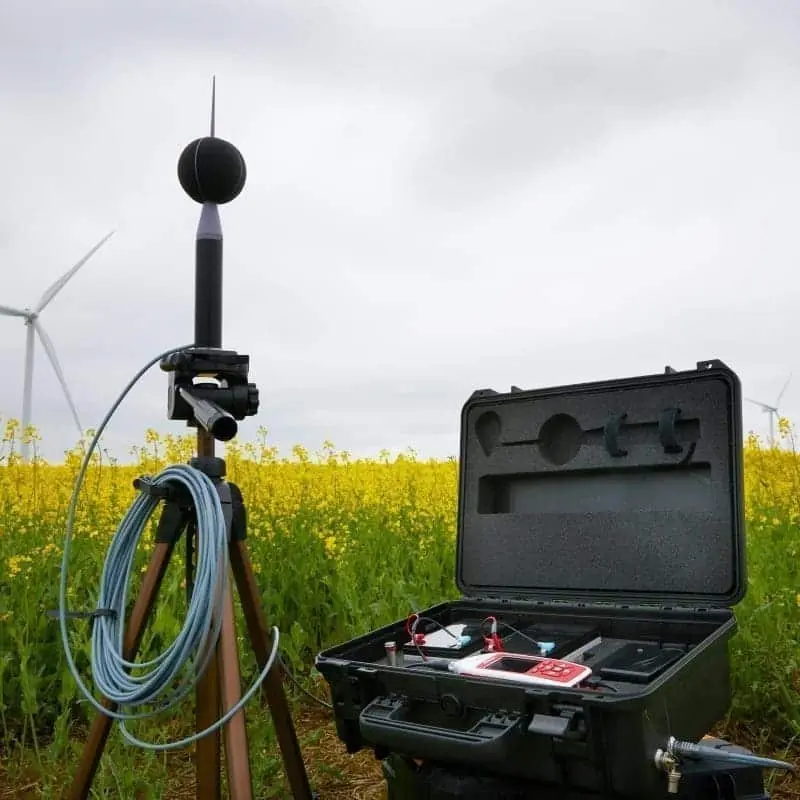 Equipo con medidor de ruido ambiental clase I sobre trípode y maleta de instrumentos realizando medición de ruido ambiental y mediciones acústicas en parque eólico, registro para evaluación SEIA (EIA/DIA).