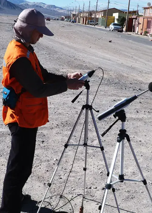 Técnico realiza medición de ruido ambiental con medidor de ruido ambiental clase I sobre trípode, registrando mediciones acústicas en zona urbana durante campaña para SEIA.