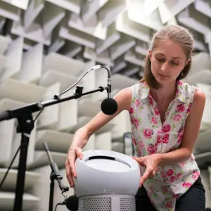 Estudio acústico en cámara anecoica con ingeniera usando micrófonos calibrados para medir niveles de ruido y analizar el comportamiento sonoro.